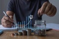 Saving money concept. businessman hand holding coins and putting in jug glass using smartphone and calculator to calculate. Royalty Free Stock Photo