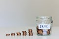 Saving money concept. Glass jar full of coins, stacks of coins and sign save Royalty Free Stock Photo