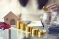 Saving money concept, Stack of gloden coin with wooden house and red car mortgage, woman hand putting coins in jug glass Royalty Free Stock Photo