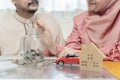 Saving money concept to buy house, car, life insurance. Muslim couple with jar of coins. Woman hand putting money in the glass jar Royalty Free Stock Photo