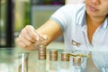 Saving money concept, woman stacking coins into increasing stack columns