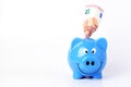 Saving money with Euro banknote into blue piggy bank Horizontal views