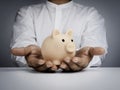 Saving money, financial, and business investment concept. Pink piggy bank is holding by businessman`s hand on white table. Royalty Free Stock Photo