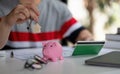 Saving money for first house or home mortgage loan concept, Man holding wooden house key chain with white piggy bank on Royalty Free Stock Photo