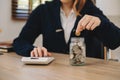 saving money with hand putting coins in jug glass and calculator to calculate budget concept finance and accounting and Gantt Royalty Free Stock Photo