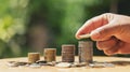 saving money hand putting coins on stack on table with sunshine. concept finance and accounting