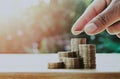 saving money hand putting coins on stack on table with sunshine. concept finance and Royalty Free Stock Photo