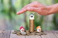 Saving money for house and real estate. Woman hand protecting on stack coins and house model on table Royalty Free Stock Photo