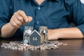 Saving money for house and real estate. Woman hand protecting on stack coins and house model on table Royalty Free Stock Photo