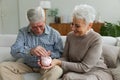 Saving money investment for future. Senior adult mature couple holding piggy bank putting money coin. Old man woman Royalty Free Stock Photo