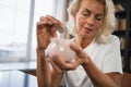 Saving money investment for future. Senior adult mature woman putting money coin in piggy bank. Old grandmother counting Royalty Free Stock Photo