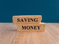 Saving money symbol. Concept words Saving money on brick blocks on a beautiful wooden table dark blue background Royalty Free Stock Photo