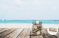 Saving money for vacation concept, glass coins container on wooden table at tropical beach