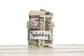 Saving money for wedding. Glass jar with us dollars on wooden table isolated