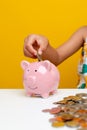 money Young girl`s hand balances coins in a piggy bank, pink pig, planting a savings plan for children, money saving Royalty Free Stock Photo