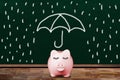Saving For a Rainy Day Concept With Piggy Bank Shielded From Rain Royalty Free Stock Photo