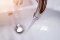 Saving water: Close up of spigot with clear, flowing water. Morning sun Royalty Free Stock Photo