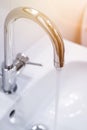 Saving water: Close up of spigot with clear, flowing water. Morning sun Royalty Free Stock Photo