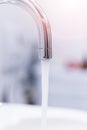 Saving water: Close up of spigot with clear, flowing water. Morning sun Royalty Free Stock Photo