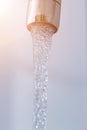 Saving water: Close up of spigot with clear, flowing water. Morning sun Royalty Free Stock Photo