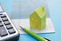 Savings account passbook, calculator, pen and yellow paper house on blue background
