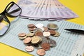 Savings account passbook, Thai money baht, coins, glasses and pen on yellow background