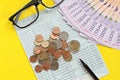 Savings account passbook, Thai money baht, coins, glasses and pen on yellow background