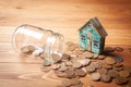 Savings concept for home. Coins are pouring from the piggy bank and the house is on them