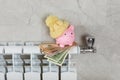 Savings concept.Money in piggy bank on radiator on a gray wall background. Royalty Free Stock Photo