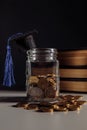 Savings for education concept. Coins in jar with coins and books. Vertical image