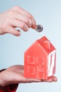 Male hand with little house and silver coin.