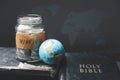 Savings jars full of money and globe with Holy Bible for mission, Mission christian idea. bible and book on wooden table, Royalty Free Stock Photo