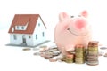 Savings for real estate project with small model house and piggy bank stanting on piles of coins Royalty Free Stock Photo
