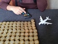 savings for travel, hand of a woman in the calculator, figure of a white airplane and stacked coins of mexican pesos