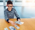 Savings, young child counting money and sitting at desk at his home. Finance or investing, financial management or Royalty Free Stock Photo