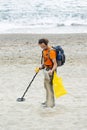 Man searching for a precious metal using a metal detector on a s