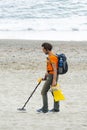 Man searching for a precious metal using a metal detector on a s