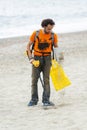 Man searching for a precious metal using a metal detector on a s