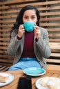 Savoring the Moment: Close-Up of a Young Latina Woman Enjoying a Delicious Coffee at the Outdoor Patio of a Cozy Cafe