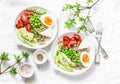 Savory breakfast grain bowl. Balanced buddha bowl with quinoa, egg, avocado, tomato, green pea on light background. Healthy diet