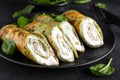 Savory crepes with spinach and feta cheese on black background