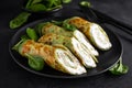 Savory crepes with spinach and feta cheese on black background