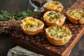 Savory mini quiches tarts on a wooden board. Flaky dough pies.