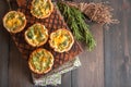 Savory mini quiches tarts on a wooden board. Flaky dough pies.