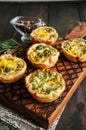 Savory mini quiches on a wooden board. Flaky dough pies on a woo