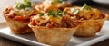 Savory mini taco cups with cheese and cilantro garnish on white plate