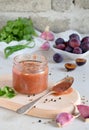 Savory sauce from red plums, garlic, cilantro, dill and hot pepper. Georgian tkemali on white background. Autumn canning and prese