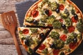 savory tart with chicken, broccoli, tomatoes and olives close-up on the table. horizontal top view