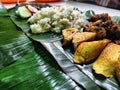 A Savory Treat: A Nasi Liwet on a Banana Leaf with a Fried Chicken, Tomato, Spicy Sambal, Cucumber, tofu and tempeh