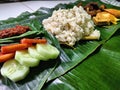 A Savory Treat: A Nasi Liwet on a Banana Leaf with a Fried Chicken, Tomato, Spicy Sambal, Cucumber, tofu and tempeh